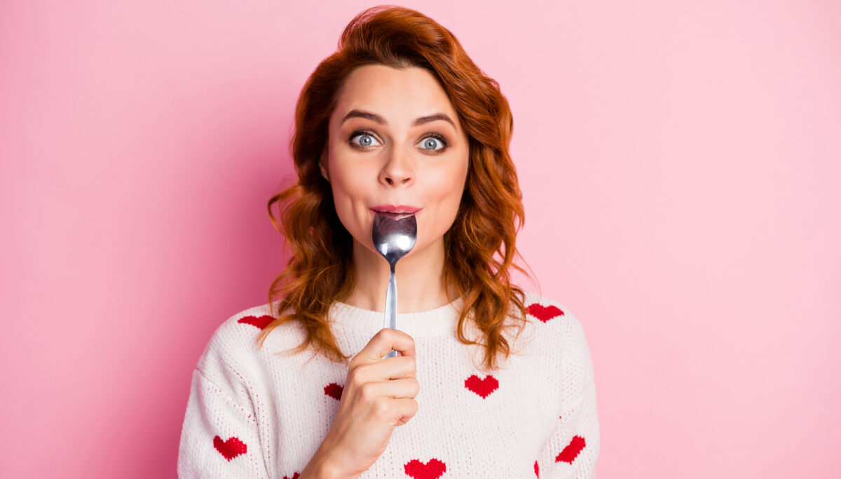 Close-up portrait of nice pretty cute glad cheerful cheery wavy-haired girl licking spoon celebratory festal lunch homemade breakfast isolated on pink pastel colour background