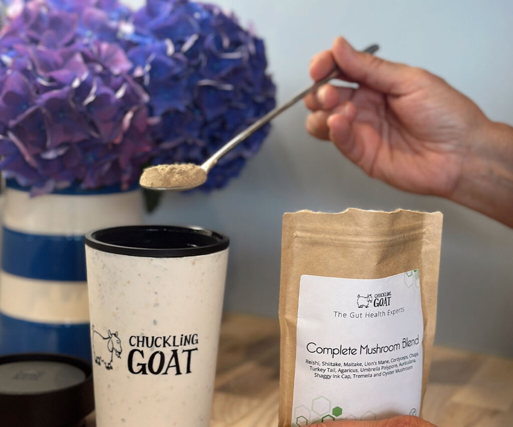 Image of Chuckling Complete Goat Mushroom Powder being added to a Chuckling Goat branded coffee travel mug.
