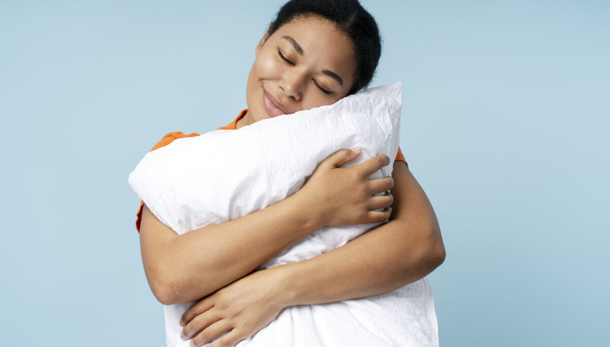 Happy woman sleeping, holding white pillow isolated on blue background. Morning concept
